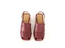 Sandalia de cuero color borgoña, con punta cuadrada y tiras anchas entrecruzadas. Tiene talón abierto con pulsera ajustable y taco ancho forrado de 4 cm.