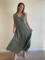 Vestido largo sin mangas, color marrón oscuro, con escote en V y corte amplio que cae hasta el tobillo. El ruedo tiene un acabado deshilachado.