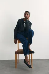 Ballerinas negras de satén, estilo guillerminas, con punta almendrada, tira sobre el empeine con hebilla dorada y taco bajo.