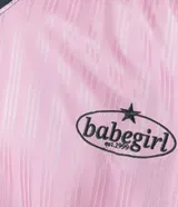 Remera rosa con cuello polo gris y rayas verticales. Estampado frontal con la palabra "gobline" en letras cursivas y la frase "in my best era". Diseño oversized con mangas cortas y recortes laterales en color negro.