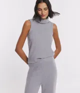 Blusa sin mangas de punto color gris, con cuello alto y superficie lisa.