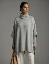 Capa o poncho tejido color verde esmeralda, con cuello polera alto que se cierra con un botón grande en el lateral. Presenta mangas cortas estilo japonesa y un calce amplio.