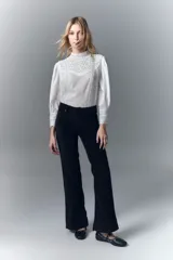 Pantalón de jean negro de pana, de tiro medio, ajustado en la cintura y con pierna levemente acampanada.