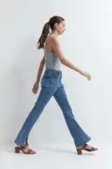 Pantalón de jean de tiro alto, corte ajustado y botamanga acampanada con tajos laterales.