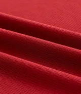 Remera de manga corta estilo polo, color rojo, con cuello y puños en contraste blanco. Presenta un corte oversized con hombros caídos y la palabra "ATHLÈTES" estampada en blanco en el frente. Incluye pequeños gráficos blancos a cada lado del pecho.