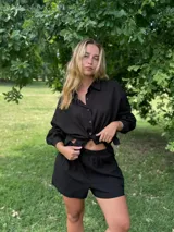 Conjunto negro de camisa de manga larga con botones y shorts.