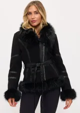 Campera negra de cuero con cuello, puños y ruedo de piel sintética. Tiene cierre frontal asimétrico, cinturón ajustable en la cintura y detalles de tiras de cuero en las mangas.