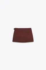 Falda pantalón color marrón óxido de tiro medio, con falsos bolsillos de vivo en la espalda y cierre frontal cruzado con botones y lateral con cremallera oculta en la costura.