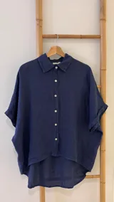 Camisa marrón de lino con botones blancos, corte holgado y mangas cortas.