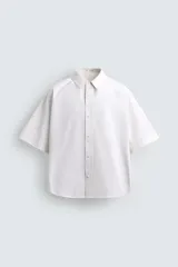 Camisa blanca de corte boxy fit, confeccionada en tejido técnico con algodón, de manga corta y cuello solapa.
