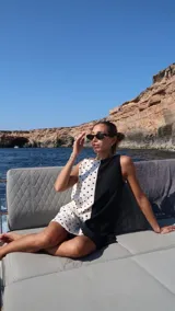 Vestido corto sin mangas, con escote recto y corte a la rodilla. Presenta un diseño bicolor, con un lado blanco con lunares negros y otro lado negro liso.