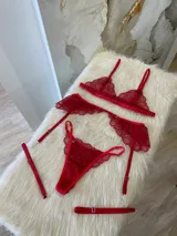 Conjunto de lencería rojo de encaje, compuesto por un bralette con breteles regulables, una tanga regulable con corte media less y un portaligas con volados.