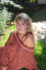 Vestido corto calado color terracota, con escote amplio y mangas largas. Incluye un accesorio tejido que puede usarse como collar o cinturón.