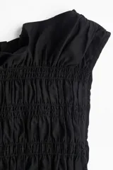 Top negro sin mangas de viscosa con diseño smock, escote barco con volados y peplum.