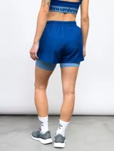 Short deportivo negro de entrenamiento para mujer, con calza interna integrada. El short exterior es de poliéster y presenta un ribete blanco en los laterales.