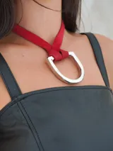 Collar con tira de cuero color suela y dije metálico dorado en forma de estribo.