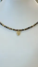 Collar de cuentas color marrón y negro con dije de leopardo dorado.