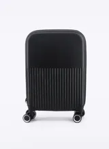Valija rígida de viaje color negro con diseño de líneas verticales en la parte inferior y cuatro ruedas dobles.