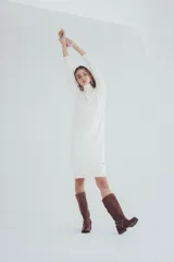 Vestido corto tejido de punto color crema, con cuello alto y mangas largas.