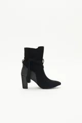 Botas de caña media de gamuza negra, con taco cuadrado y punta fina. Presenta tiras terminadas con borlas que se cruzan y atan alrededor de la caña.