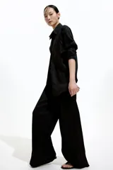 Pantalón negro de punto con cintura elástica y cordón ajustable. Corte holgado con piernas anchas y tiro alto.