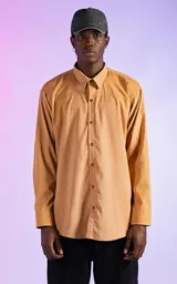 Camisa manga larga color mostaza de calce relaxed fit. Cuenta con detalles de canesú en frente y espalda, y aberturas en laterales. Su tela gamuzada le brinda a la prenda una textura de exclusiva suavidad.