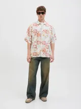 Camisa de manga corta con cuello resort y fit amplio, confeccionada en tejido plano de lino y algodón. Presenta un estampado de mosaicos en tonos rojo, naranja, azul y blanco.