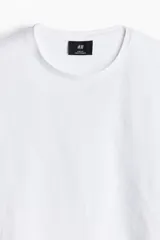 Remera blanca de algodón liviano con cuello redondo ribeteado y bajo recto. Corte ajustado que realza el contorno del cuerpo creando una silueta entallada.