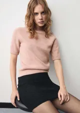 Sweater de punto color rosa, con cuello alto y mangas cortas.