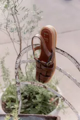 Sandalias de cuero marrón con tiras entrecruzadas y hebilla dorada al tobillo.