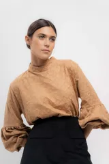 Camisa color camel con estampado geométrico, cuello alto y mangas largas abullonadas con puños elásticos.