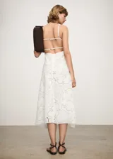 Vestido midi blanco de encaje con tirantes finos, escote cuadrado, corte en la cintura y falda acampanada. Presenta aberturas laterales en la cintura y bajo asimétrico.