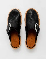 Mocasines negros de cuero con hebilla plateada y suela de cuero color natural.