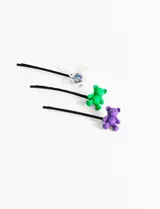 Set de tres horquillas negras para el pelo, cada una decorada con un pequeño oso de goma: uno transparente con detalles brillantes, uno verde y uno violeta.