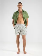 Short de baño celeste con rayas verticales blancas y estampado de flores blancas.