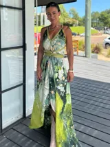 Vestido largo de tela fluida, color verde esmeralda con estampado abstracto en tonos turquesa y detalles dorados. Diseño asimétrico con un solo tirante tejido en el hombro.