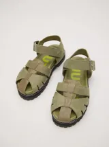 Sandalias romanas color verde oliva, con tiras entrecruzadas y hebilla lateral. Suela de goma negra con plataforma de 3cm. Fabricadas en cuero vacuno.