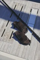 Sandalias marrones de cuero con flecos y apliques metálicos.