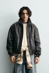 Cazadora bomber de piel color marrón oscuro envejecido, con cuello solapa, cierre frontal de cremallera y puños y bajo en rib elástico. Presenta grabados en relieve en el delantero y la espalda.