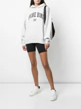 Hoodie gris jaspeado de algodón con capucha, corte oversize, bolsillo tipo canguro y estampado en el frente con el logo "ANINE BING SPORT" en letras de estilo universitario.