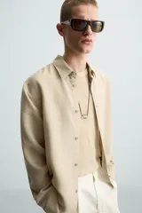 Camisa de manga larga color celeste claro, con cuello solapa y cierre frontal de botonadura. Presenta una textura sutil en el tejido.