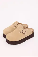 Zuecos color beige con plataforma marrón, capellada de símil gamuza, detalle de costuras artesanales y hebilla regulable.