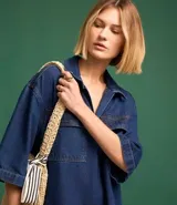 Vestido corto de jean azul con cuello camisero, escote en V, mangas cortas, dos bolsillos delanteros y corte recto.