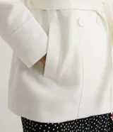 Campera alargada color blanco, confeccionada en polivelour, con cuello alto doblable, mangas largas, abotonado frontal doble, bolsillos y cinturón.