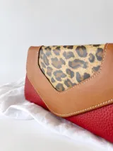 Billetera de cuero color rojo con solapa de cuero color marrón y aplique de cuero con estampado animal print.