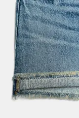 Shorts de jean de algodón, tiro alto, color azul claro desgastado. Presenta cinco bolsillos, cierre frontal con botón metálico y bajo desflecado con vuelta.