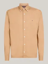 Camisa color beige de corte regular, confeccionada en algodón elástico. Cuenta con cuello abotonado, mangas largas con puños abotonados y logo de Tommy Hilfiger bordado en el pecho.
