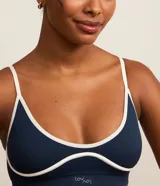 Soutien deportivo azul con breteles finos ajustables, base larga y detalles contrastantes en color blanco.