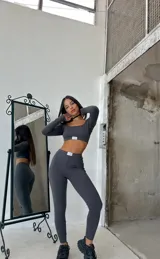 Conjunto deportivo gris compuesto por un top corto de manga larga y calzas largas ajustadas.