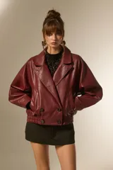 Campera estilo biker de eco-cuero color bordó, con cuello solapa ancho, manga larga y calce holgado. Presenta cierre frontal y botones decorativos en la parte inferior delantera.